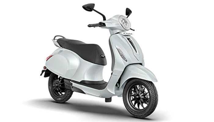 Chetak urbane 2024 - tycoonstory | tycoonstory media White electric scooter designed in a retro style with black seat, round headlight and side mirrors.