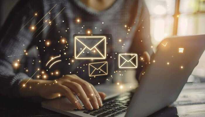 Email marketing automation - tycoonstory | tycoonstory media A person typing on a laptop with glowing email icons floating around, representing the concept of marketing automation services and automated email marketing