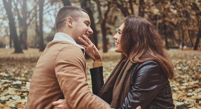 Explore new activities as partners - tycoonstory | tycoonstory media A couple sitting close together in a park, smiling warmly at each other and sharing an intimate moment,