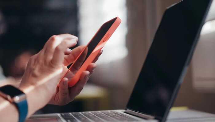 Person using smartphone and laptop, showing fintech and payment solutions in niches in app development. Niches in app development