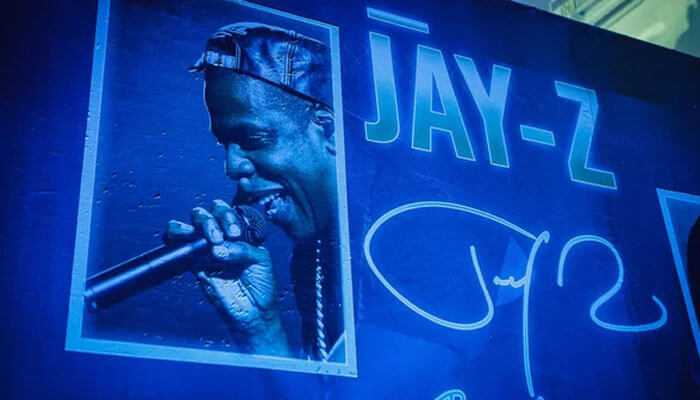 Future prospects and earnings - tycoonstory | tycoonstory media Portrait of jay-z signing on a blue-toned wall, showing how iconic he is and the influence on jay z net worth.