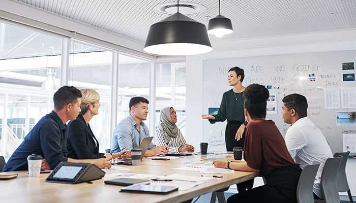 Managing group dynamics - tycoonstory | tycoonstory media A focus group moderator leads a diverse group discussion in a modern office setting, showcasing effective focus group moderation techniques for gathering consumer insights