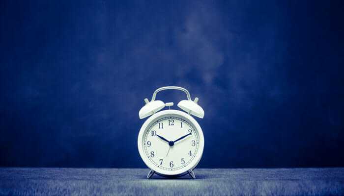 Minimize downtime - tycoonstory | tycoonstory media A classic white alarm clock against a dark blue background, symbolizing time management and reliability, representing it support for businesses in england