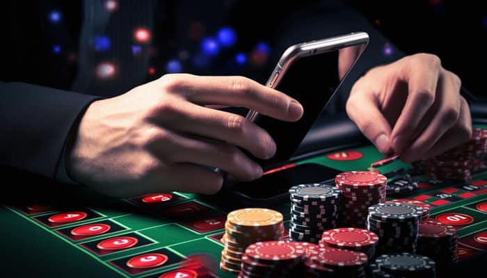 Tips for safe and responsible gaming - tycoonstory | tycoonstory media Close-up of a person's hands holding a smartphone while placing bets with poker chips on a casino table, illustrating playing on the MCW Casino App.
