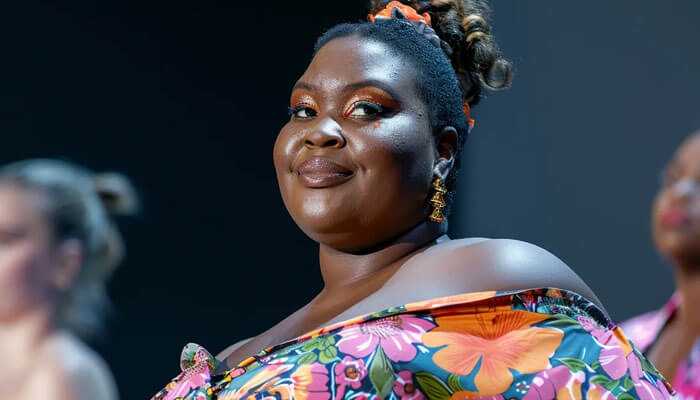 Sustainable plus-size fashion gains momentum - tycoonstory | tycoonstory media Plus-size model strutting in bright floral off-the-shoulder dress down the runway with confidence.