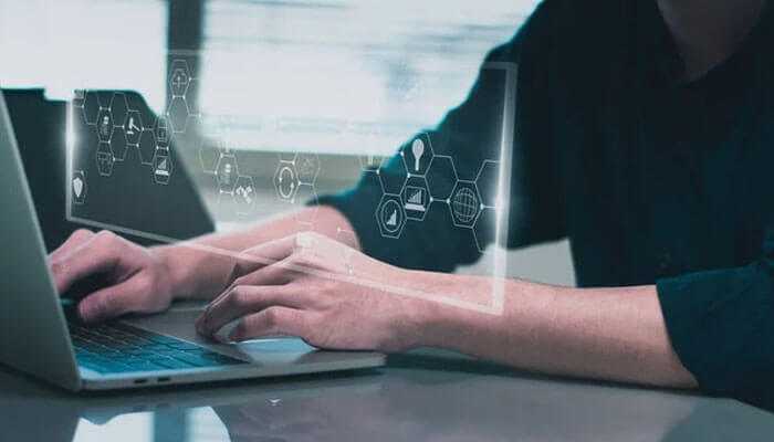 The need for competitive advantage a conceptual analysis - tycoonstory | tycoonstory media Person typing on laptop with holographic data analytics icons on display, representing mobile app market research and conducting analysis.