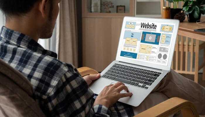 5 benefits of user-centered website design - tycoonstory | tycoonstory media A person seated, using a laptop displaying a website design interface, suggesting user-centered website design and development