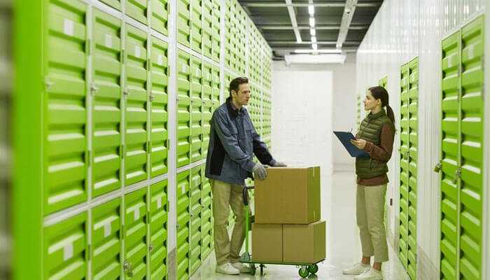 A cost-effective storage solution - tycoonstory | tycoonstory media Business storage solutions with a man and woman in a secure self-storage facility with green storage units, showcasing organized storage options for businesses