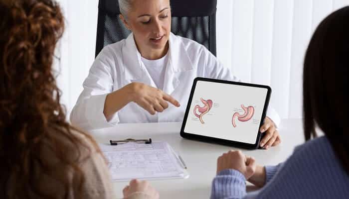 Benefits of attending a consultation before bariatric surgery - tycoonstory | tycoonstory media Professional consultation setting where a bariatric surgeon is explaining surgical options using an illustration of the stomach anatomy on a tablet.