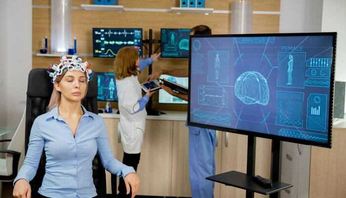 Brain-machine interfaces plugged in or freaked out - tycoonstory | tycoonstory media Woman wearing a brainwave headset in a futuristic lab, highlighting how tech will change your world.