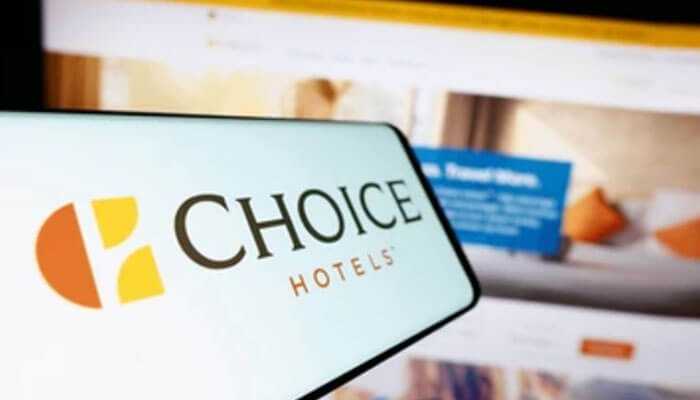 Choice hotels international - tycoonstory | tycoonstory media Choice hotels logo displayed on a smartphone screen with a blurred hotel booking website in the background, representing a new jersey franchise