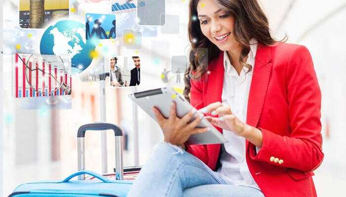 Ensuring compliance and efficient expense control - tycoonstory | tycoonstory media Smiling woman in a red blazer using a tablet at an airport, with digital graphics of business charts, travel, and networking.