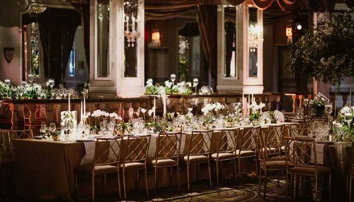 Glamorous vintage wedding - tycoonstory | tycoonstory media Wedding themes perfect for winter luxurious indoor reception with elegant long tables golden chairs white floral arrangements chandeliers and soft ambient lighting
