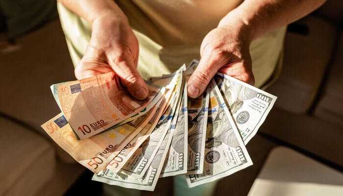 Higher profits - tycoonstory | tycoonstory media Hands holding euro and dollar bills, representing earnings potential in the secondary ticket market through ticket reselling and flipping opportunities