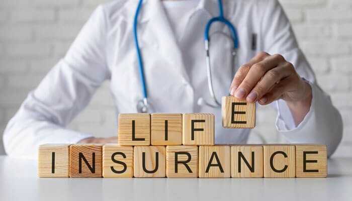 How to get life insurance after being diagnosed with diabetes - tycoonstory | tycoonstory media Doctor arranging wooden blocks spelling life insurance, symbolizing financial security and life insurance for diabetic patients and other individuals seeking health coverage options