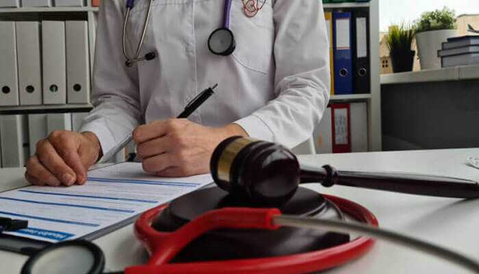 Keeping records - tycoonstory | tycoonstory media A doctor fills out personal injury case documentation on a desk with a stethoscope and a gavel: the sign of combined medical and legal responsibilities.