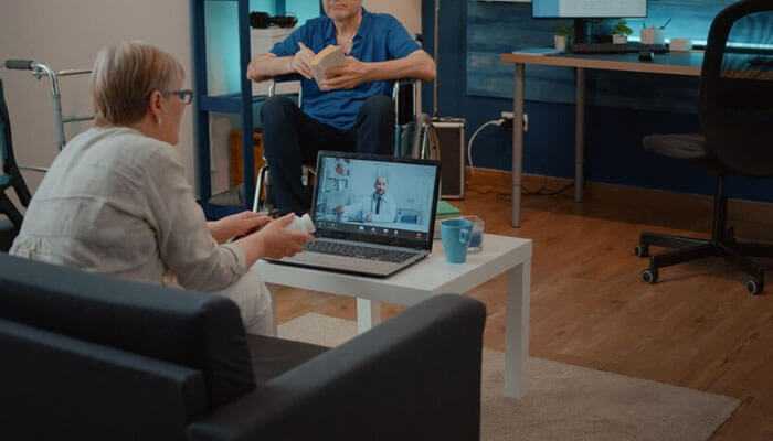 Keeping your agency in compliance with governmental guidelines - tycoonstory | tycoonstory media Home health care software streamlining agency operations featuring a caregiver using a laptop for telehealth consultation with a patient in a wheelchair nearby