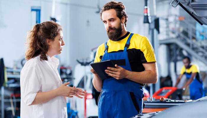 Knowing walmart auto center prices - tycoonstory | tycoonstory media A mechanic in a walmart auto center discussing car repairs with a customer, using a tablet to explain the issues.