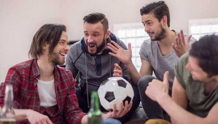 Mutual support eases defeat - tycoonstory | tycoonstory media A group of friends enthusiastically discussing a soccer game while holding a ball symbolizes sports wagering with friends.