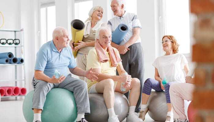 Rehab centers rebuilding relationships - tycoonstory | tycoonstory media A group of elderly individuals in rehab, seated on large exercise balls, grasping yoga mats and having a light-hearted discussion.