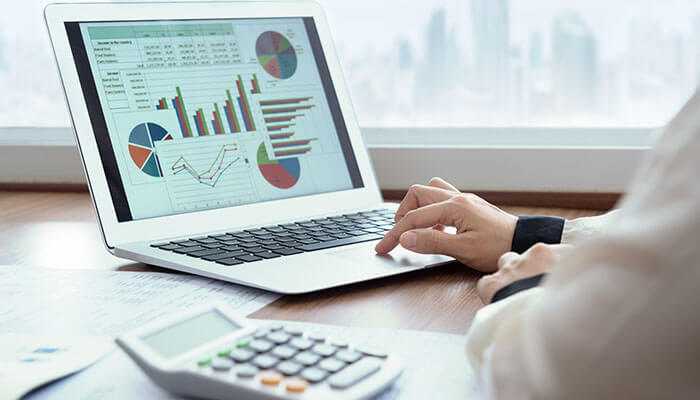 Researching market standards and trends - tycoonstory | tycoonstory media A person analyzes employee benefits data charts on a laptop with a calculator nearby