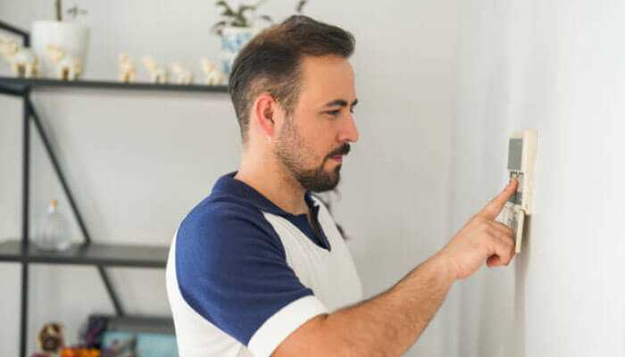 Seamless integration with smart technology - tycoonstory | tycoonstory media Man operating a wall-mounted remote control switch to change settings on home energy.