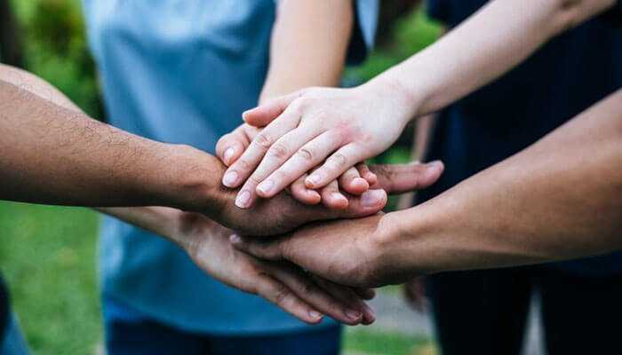 Social trust - tycoonstory | tycoonstory media Group of people stacking their hands together in a gesture of teamwork and unity, symbolizing collaboration, trust, mutual support, and influencer marketing.