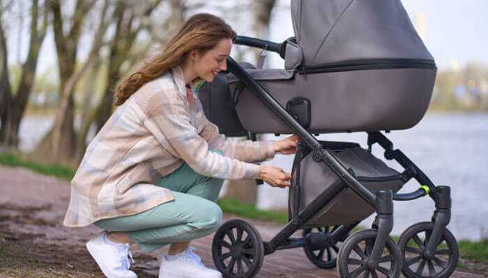 Stylish and versatile design - tycoonstory | tycoonstory media Mother adjusting a storage compartment on a high quality baby stroller while going out for an outdoor stroll.