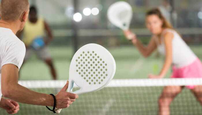 The use of carbon fiber - tycoonstory | tycoonstory media Players in a game of padel racket with a paddle in their hands ready to return the ball over the net.
