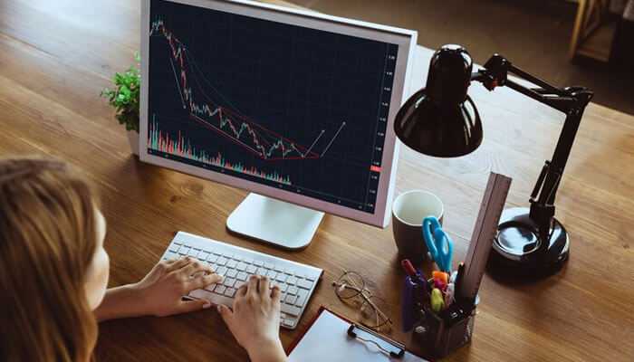 Trading with stocks and demat accounts - tycoonstory | tycoonstory media Person analyzing stock market trends on a computer screen with candlestick chart, exploring options for opening a demat account.