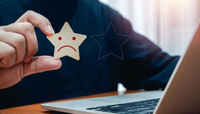 What are the consequences of a damaged personal reputation - tycoonstory | tycoonstory media A person holding a sad face star, representing poor personal reputation or negative feedback online.