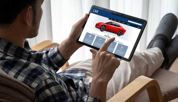 Where to find accurate car valuations - tycoonstory | tycoonstory media Man browsing a car-selling website on a tablet, showcasing a red car with detailed features and specifications, exploring options to sell your car