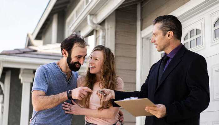 Affordability meets luxury - tycoonstory | tycoonstory media A smiling couple receiving house keys from a real estate agent outside a modern home, displaying conway south carolina homes.