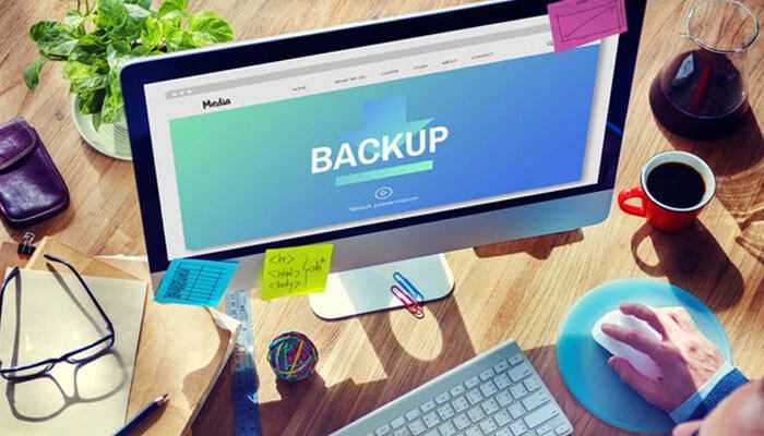 Backup and restore - tycoonstory | tycoonstory media Aapanel: computer screen displaying'BACKUP' with the interface open, surrounded by office supplies, coffee, and plants on the desk.