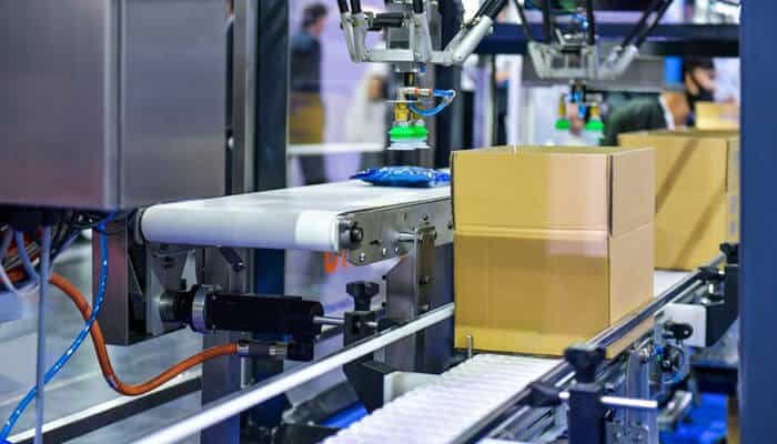 Better productivity - tycoonstory | tycoonstory media Automatic conveyor accessories in manufacturing with a robotic arm packaging boxes.