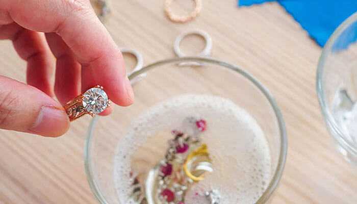 Dish soap solution - tycoonstory | tycoonstory media Clean moissanite jewelry: a diamond ring in a person's hand over a bowl of soapy water.