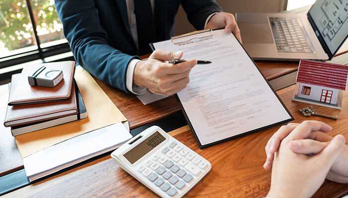 Documentation required for claiming hra exemption - tycoonstory | tycoonstory media A professional meeting with documents, a calculator, a laptop, and a house model, suggesting a discussion about house rent allowance or real estate