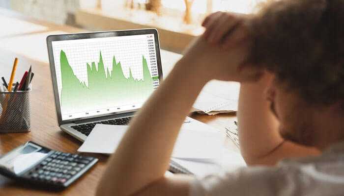 Emotional influences on investment behavior - tycoonstory | tycoonstory media A person reviewing a green financial chart on a laptop, reflecting concepts of behavioral finance and decision-making.