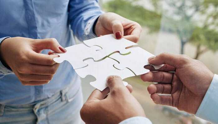 Encourage collaboration - tycoonstory | tycoonstory media Viral campaigns four individuals collaboratively holding puzzle pieces to form a complete picture symbolizing teamwork and partnership for creating viral campaigns