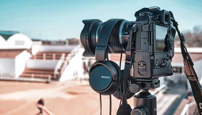 Evaluate their values and ethics - tycoonstory | tycoonstory media A professional camera on a tripod with sony headphones, set up outdoors, representing a video production company