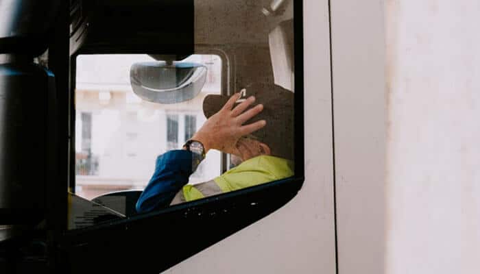 Fatigued driving - tycoonstory | tycoonstory media A truck driver in a high-visibility jacket, sitting inside a truck resting his hand on his head, perhaps reflecting on all the hos violations.