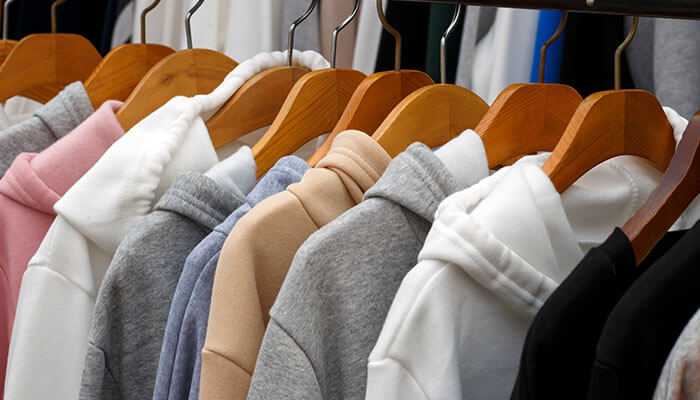 How to start a hoodie business - tycoonstory | tycoonstory media Hoodies in various colors on hangers are perfect inspiration to start a hoodie business.