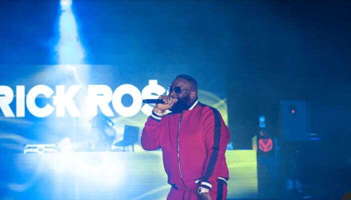 Income from music sales - tycoonstory | tycoonstory media Rick ross performing on stage in a red tracksuit, showcasing his musical talent and success, contributing to his impressive rick ross net worth.