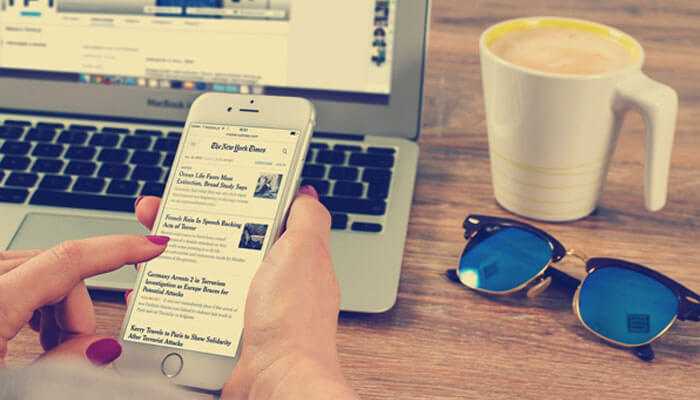 Online casino platforms - tycoonstory | tycoonstory media A person browsing articles on a smartphone with a laptop and coffee nearby; linked to make money in casino business.