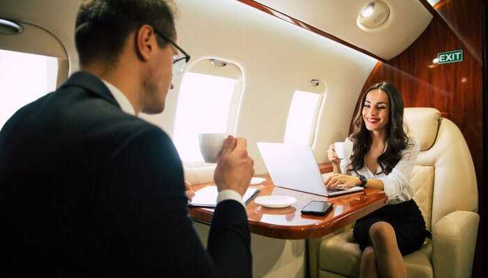 Privacy - tycoonstory | tycoonstory media Business professionals discussing and enjoying coffee onboard corporate jet charters, with a laptop and mobile phone on the table.