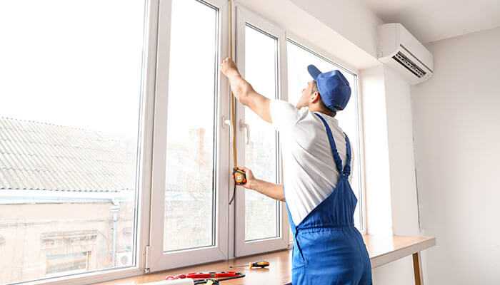 Proactive maintenance practices - tycoonstory | tycoonstory media Apartment property manager measuring and inspecting window fittings in a modern apartment, ensuring maintenance and tenant satisfaction