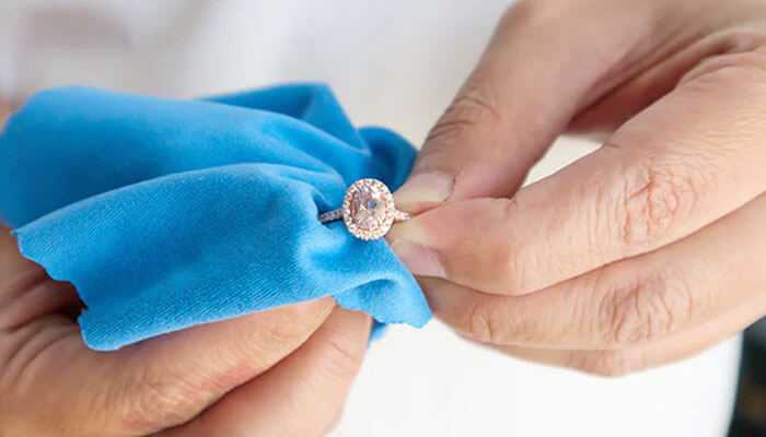 Professional cleaning - tycoonstory | tycoonstory media Close-up of a person polishing a diamond ring with a blue microfiber cloth.