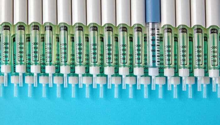 Quality supervision - tycoonstory | tycoonstory media Medical injection molding with syringes containing green liquid arranged neatly on a blue background
