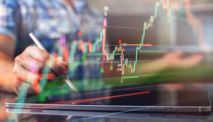 Risks associated with high dividend yield investing - tycoonstory | tycoonstory media A person holding a stylus, interacting with a digital tablet displaying colorful stock market charts, highlighting high dividend yields.