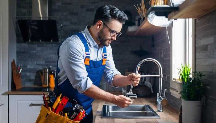 Selecting the appropriate emergency plumber in san diego - tycoonstory | tycoonstory media Emergency plumber in san diego fixing a faucet in a modern kitchen with wooden countertops and natural light